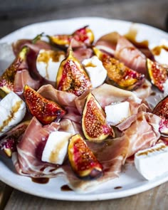 figs, prosciutto and cheese on a white plate sitting on a wooden table