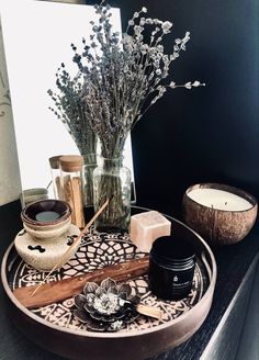 a wooden tray topped with candles and vases