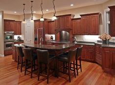 a large kitchen with wooden floors and dark wood cabinetry, along with bar stools