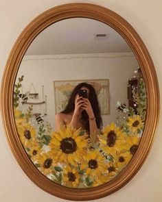 a woman taking a selfie in front of a mirror with sunflowers on it