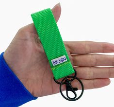 a hand holding a green lanyard with a black ring on it's end