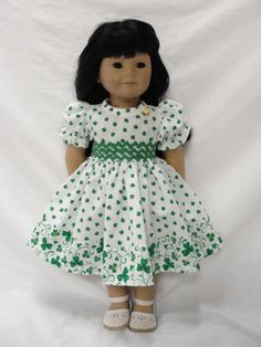 a doll with black hair wearing a white dress and green shamrocks on it's chest