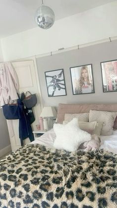 a bedroom with pictures on the wall and a leopard print bed spread in front of it