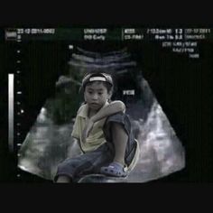 a young boy sitting on top of a skateboard in front of a computer screen