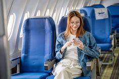 a woman sitting on an airplane looking at her phone