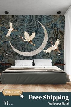 a bed sitting in front of a wall with two birds flying over the moon on it