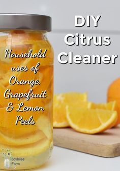 a glass jar filled with oranges and lemon peels next to a cutting board