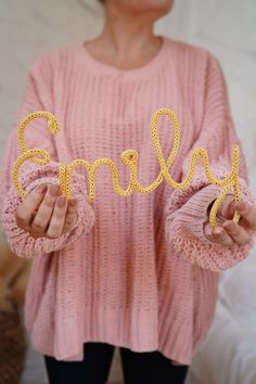 a woman holding up the word smile spelled out with her hands in front of her