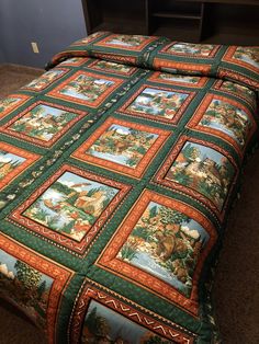 a bed with a green and orange quilt on top of it next to a night stand