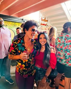 two women standing next to each other in front of a group of people at a party