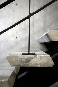 a black and white photo of a bench with metal bars on the bottom, in front of a concrete wall