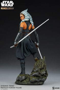 a star wars action figure is posed on top of a rock with two swords in his hand