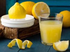 a glass of lemon juice next to sliced lemons