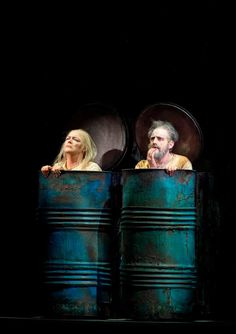 two people are sitting in large metal barrels