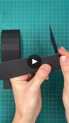 someone is cutting out a piece of black paper with a pair of scissors on it