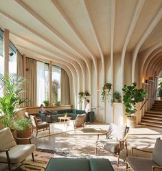 a living room filled with lots of furniture next to a stair case covered in potted plants