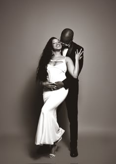 a black and white photo of a man and woman in formal wear hugging each other