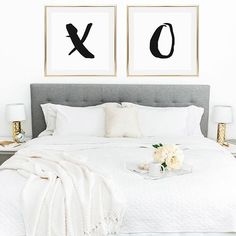 two black and white paintings on the wall above a bed in a bedroom with pillows