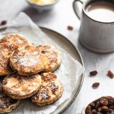 some food is on a plate and next to a cup of coffee, beans and milk