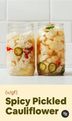 two jars filled with pickled cauliflower and cucumbers