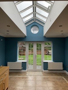 an empty room with blue walls and skylights