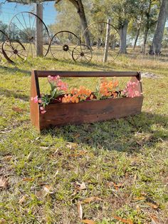 a wooden planter filled with flowers in the grass