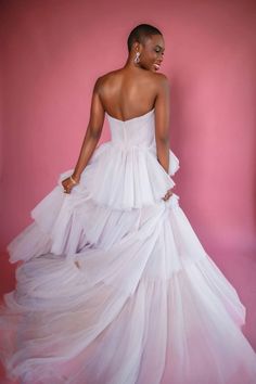 a woman in a white dress standing against a pink background