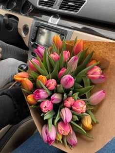 a bouquet of tulips sits in the passenger seat of a car