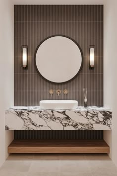 a bathroom with a marble counter top and round mirror above the sink, along with two wall sconces