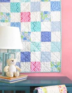 a white teddy bear sitting on top of a table next to a lamp and blanket