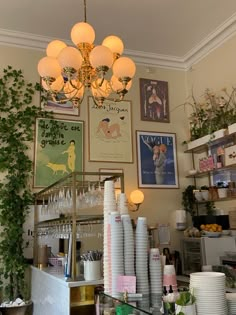 there are many plates and cups on the counter in this restaurant with plants growing up against the wall