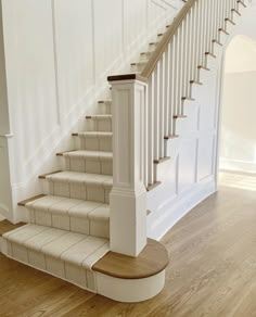 a white staircase with wooden handrails and carpeted steps leading up to the second floor