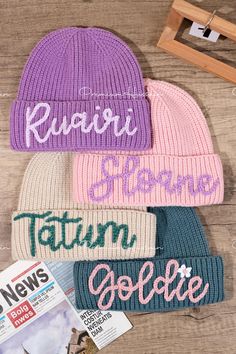 three knit beanies with the word news written on them, one in pink and one in blue