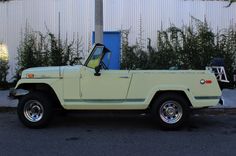 an old yellow jeep parked in front of a building