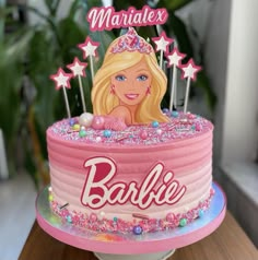 there is a barbie cake on top of the table with pink frosting and stars