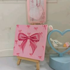 an easel with a pink bow on it next to a mirror and other items