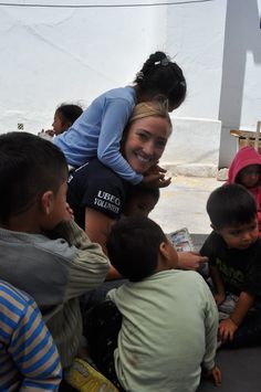 a woman sitting on the ground surrounded by children