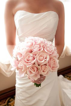 a bride holding a bouquet of pink roses