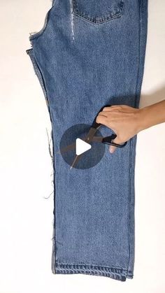 someone is cutting through the hole in a pair of jeans