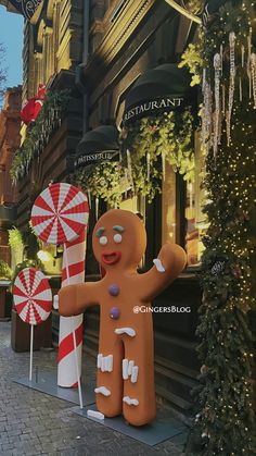 giant gingerbread man and candy canes in front of a building on the street