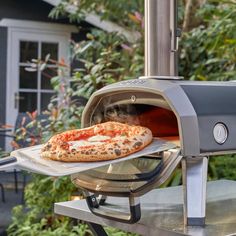 a pizza sitting on top of an outdoor grill with a pizza in it's tray