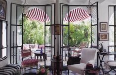 a living room filled with lots of furniture and windows covered in red and white curtains