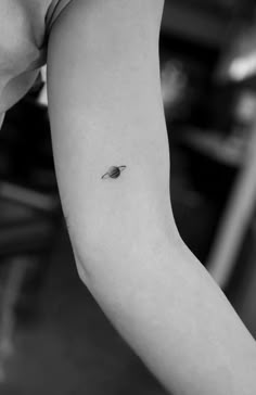 a small saturn tattoo on the left inner arm and shoulder, it is black and white