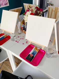 two easels are sitting on a table with paints and pencils