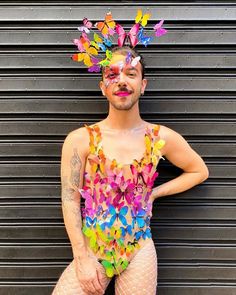 a man with butterflies painted on his face and body standing in front of a garage door