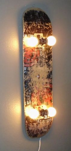 a skateboard with some lights on it hanging from the side of a white wall