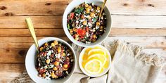 two bowls filled with food sitting on top of a wooden table next to an orange slice