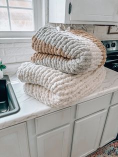 three towels stacked on top of each other in front of a kitchen sink and stove