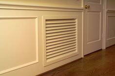 an empty room with white paneling and wood flooring on the side of the wall