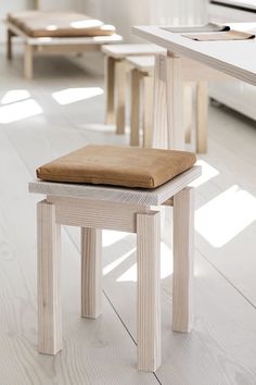 a wooden bench sitting on top of a hard wood floor next to a white table